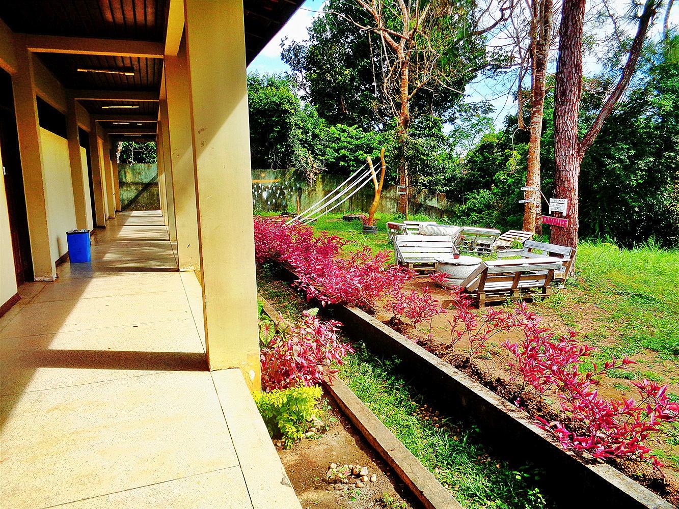 Área de convivência de campus universitário com bancos e jardim.